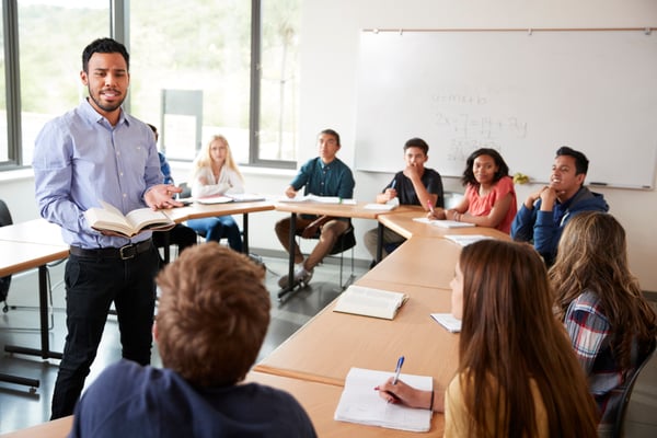 male-high-school-tutor-with-pupils-sitting-at-tabl-2024-10-22-04-17-04-utc