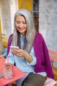 pretty-senior-asian-lady-reads-sms-on-mobile-phone-AGXLJZM