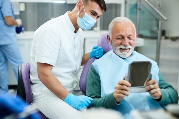 satisfied-senior-man-looking-his-teeth-in-a-mirror-2022-11-09-03-48-34-utc