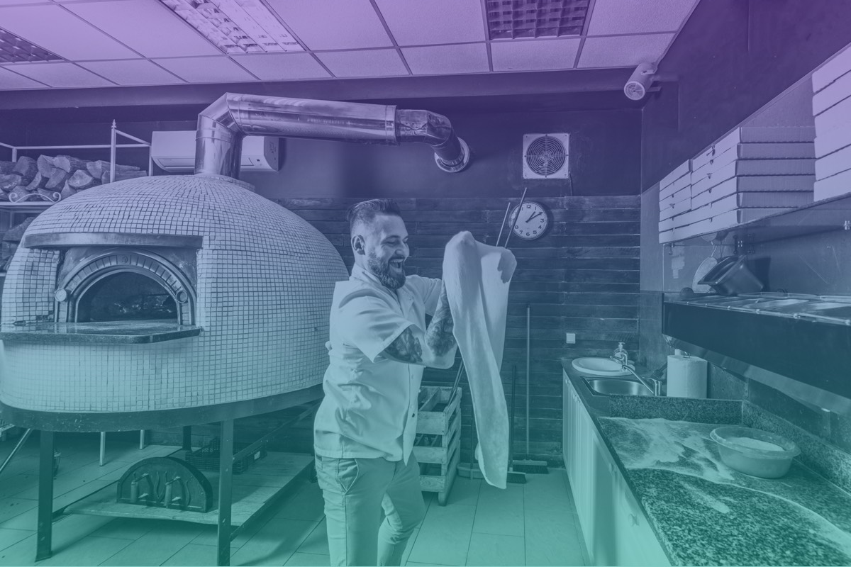 Employee tossing pizza dough.